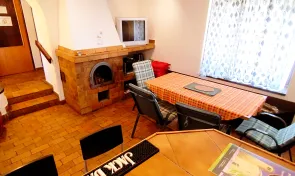 Společenská místnost s krbem, vstupem do kuchyňky a sauny